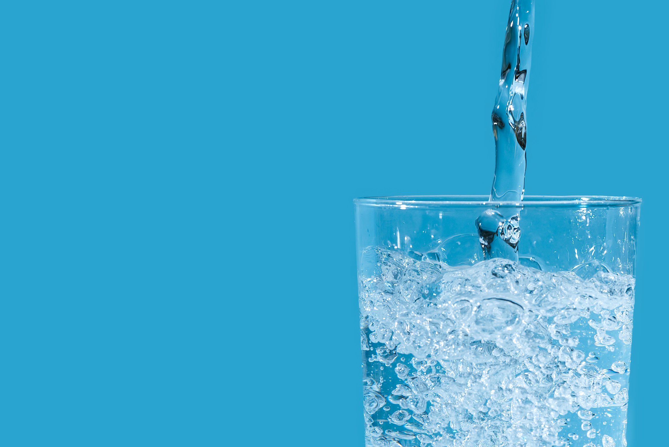 Pouring clean drinking water from blue plastic bottle into glass on blue background