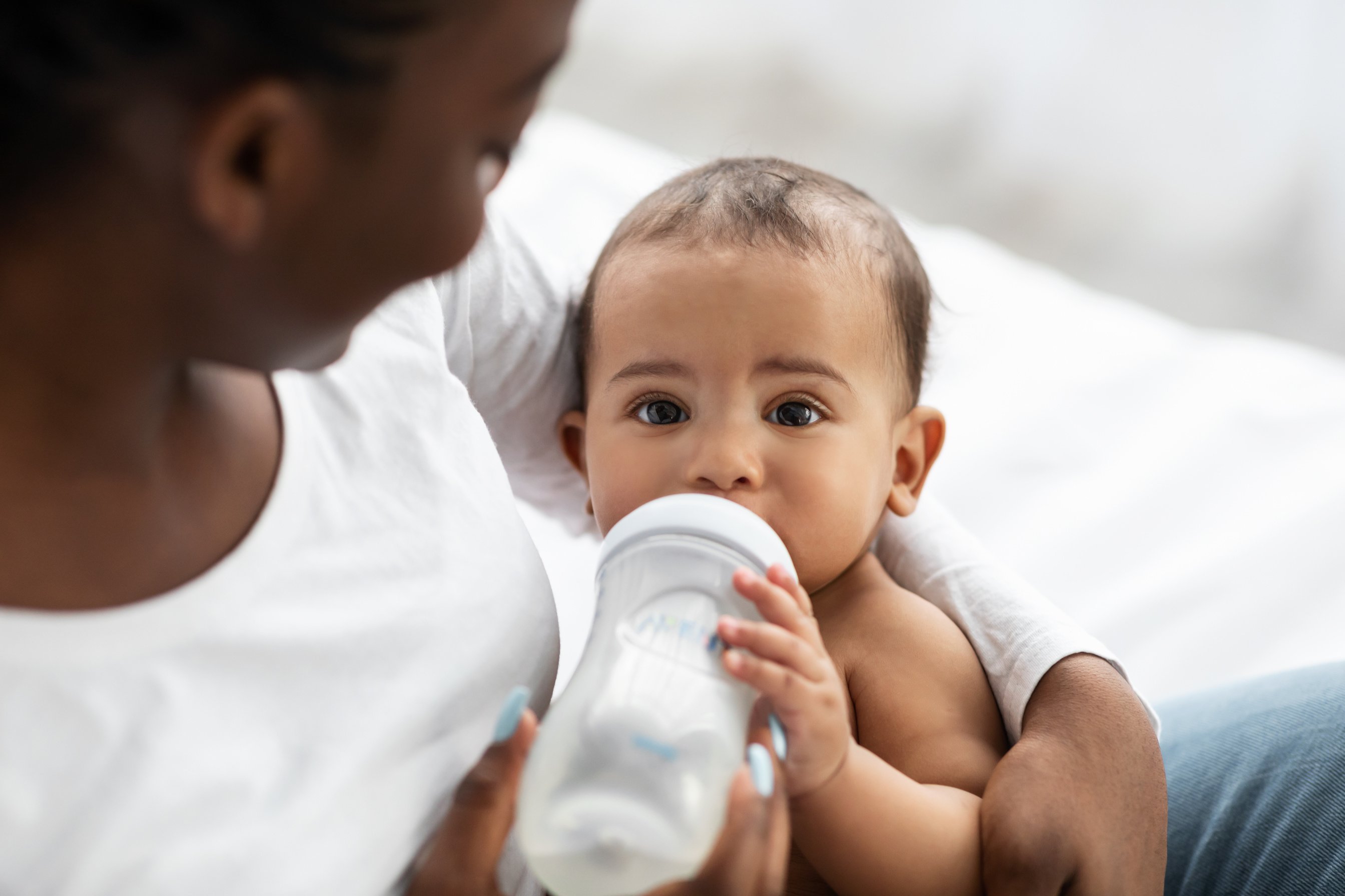 Cute little African American baby drinking from baby bottle